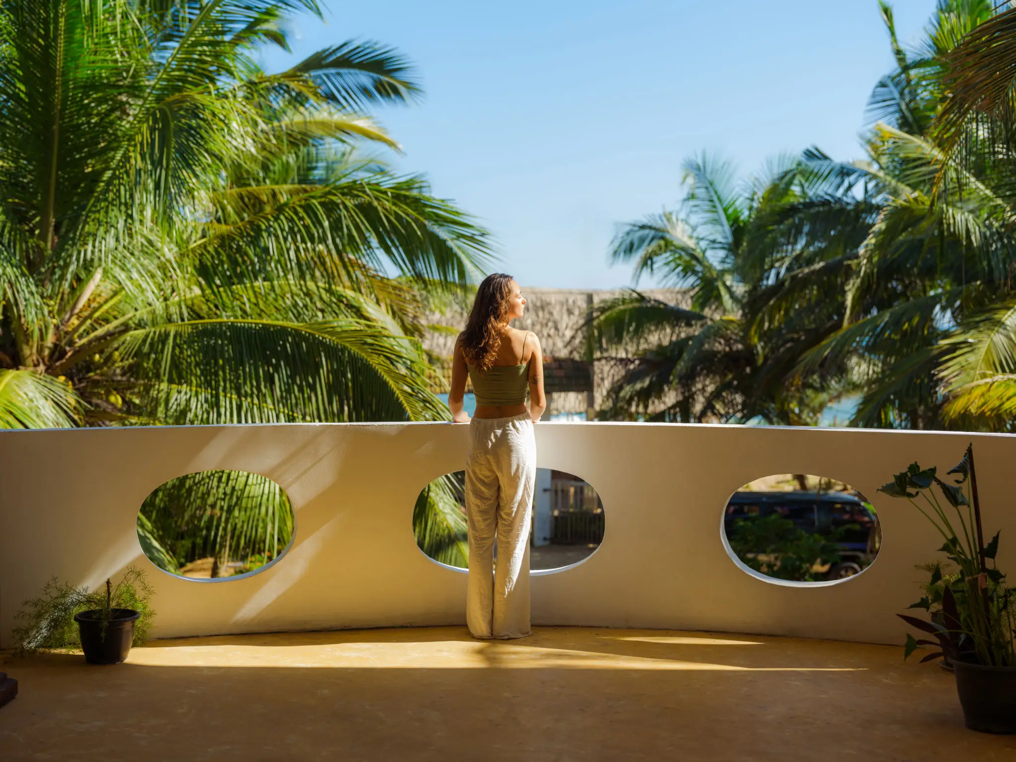 Person on tropical balcony overlooking palm trees