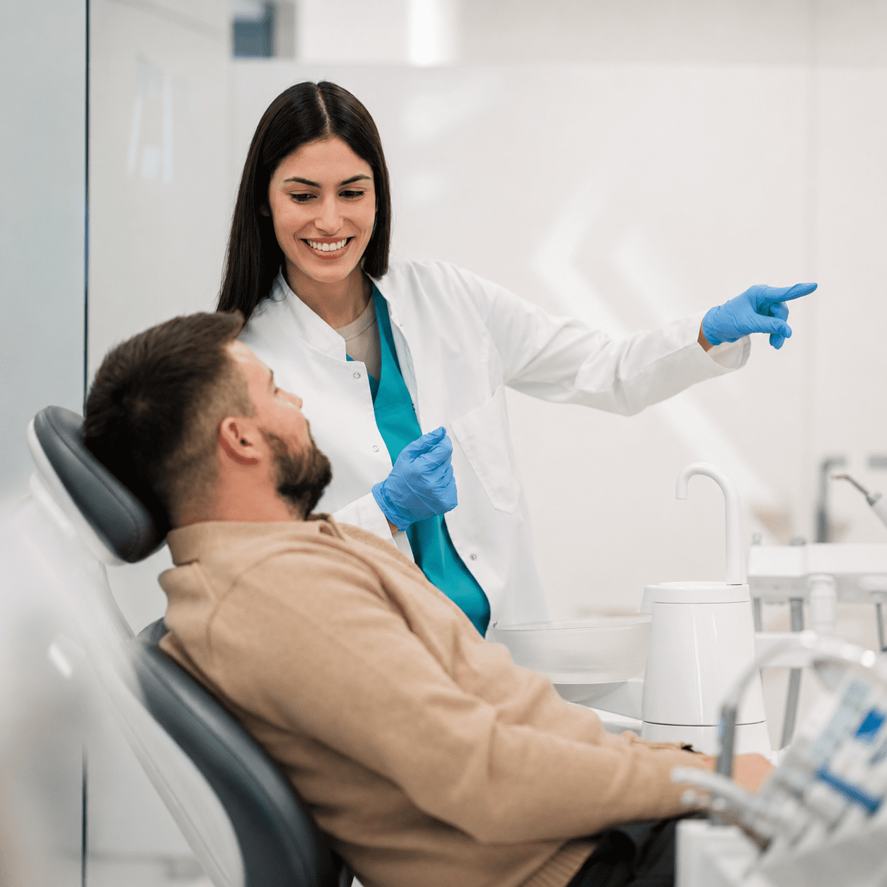 Dentist pointing while patient reclines in chair